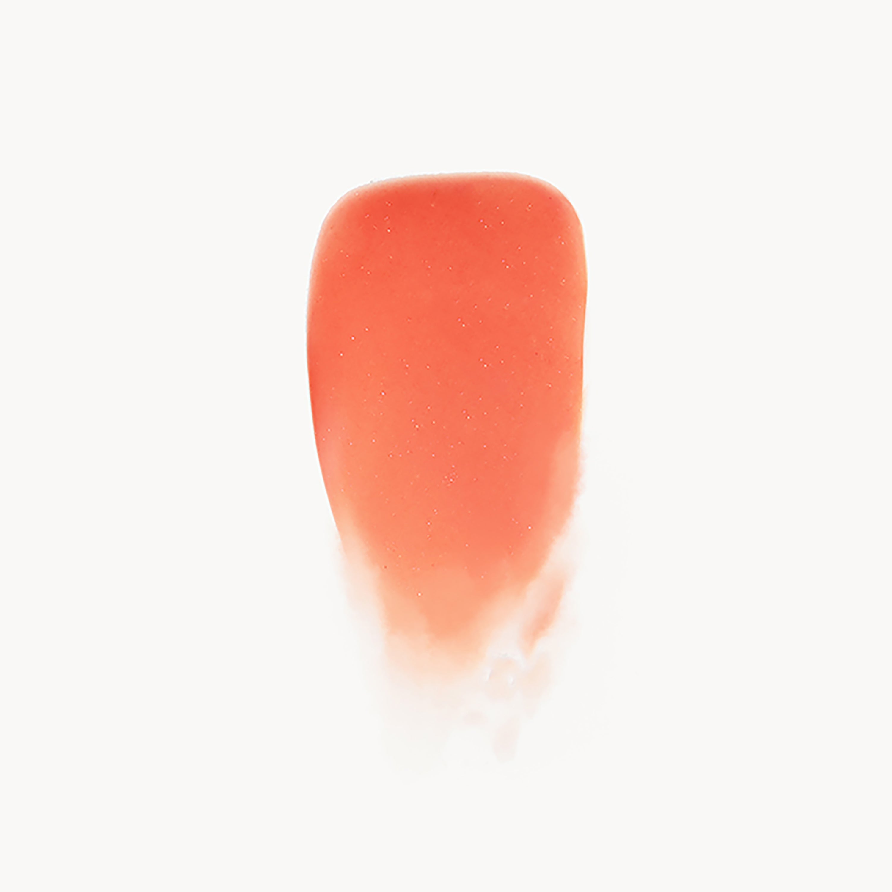 Close-up of a coral-colored lip gloss swatch on a white background