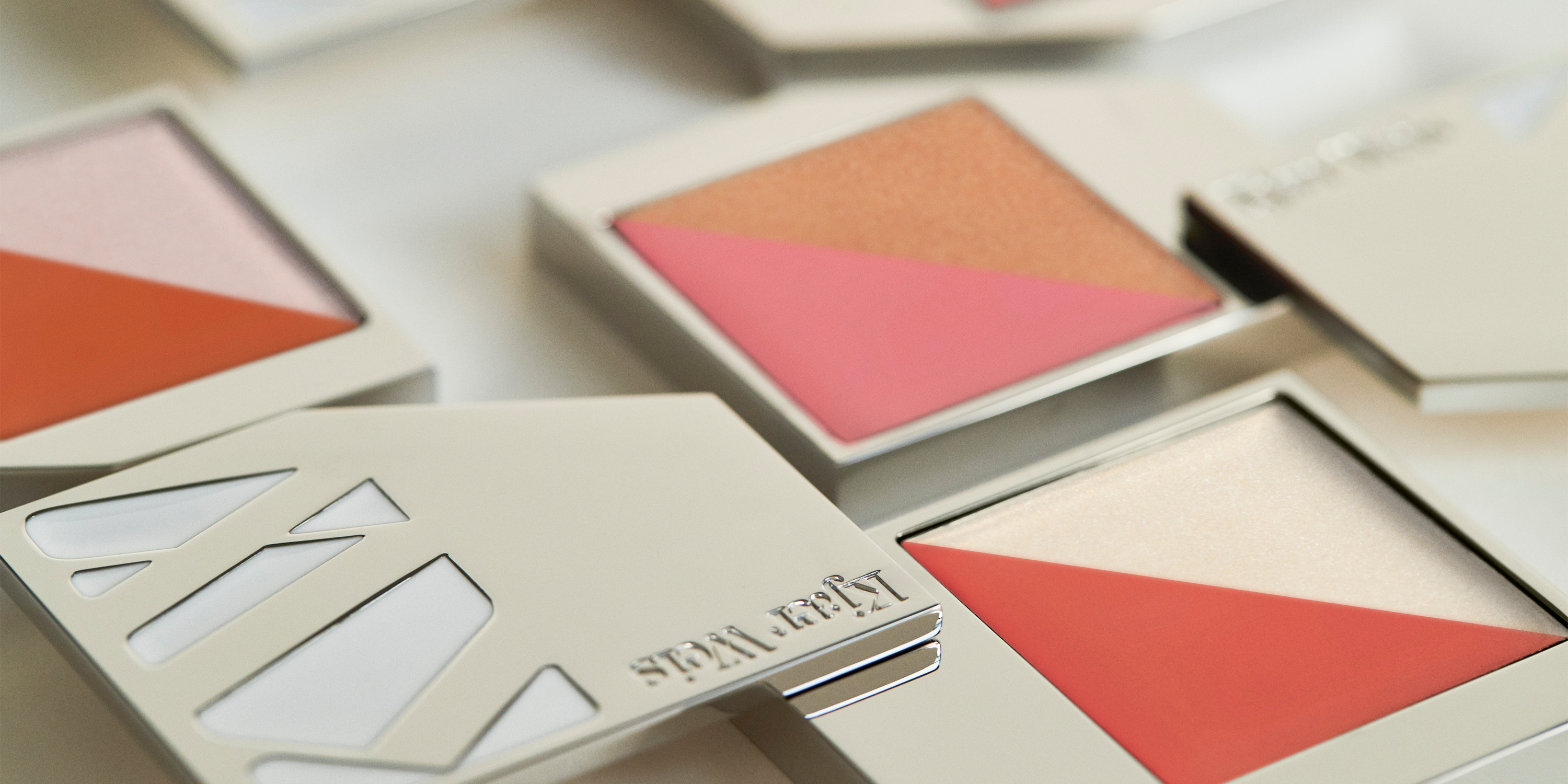 Various shades of the Kjaer Weis Flush & Glow Duo in the Iconic Edition case on a light background