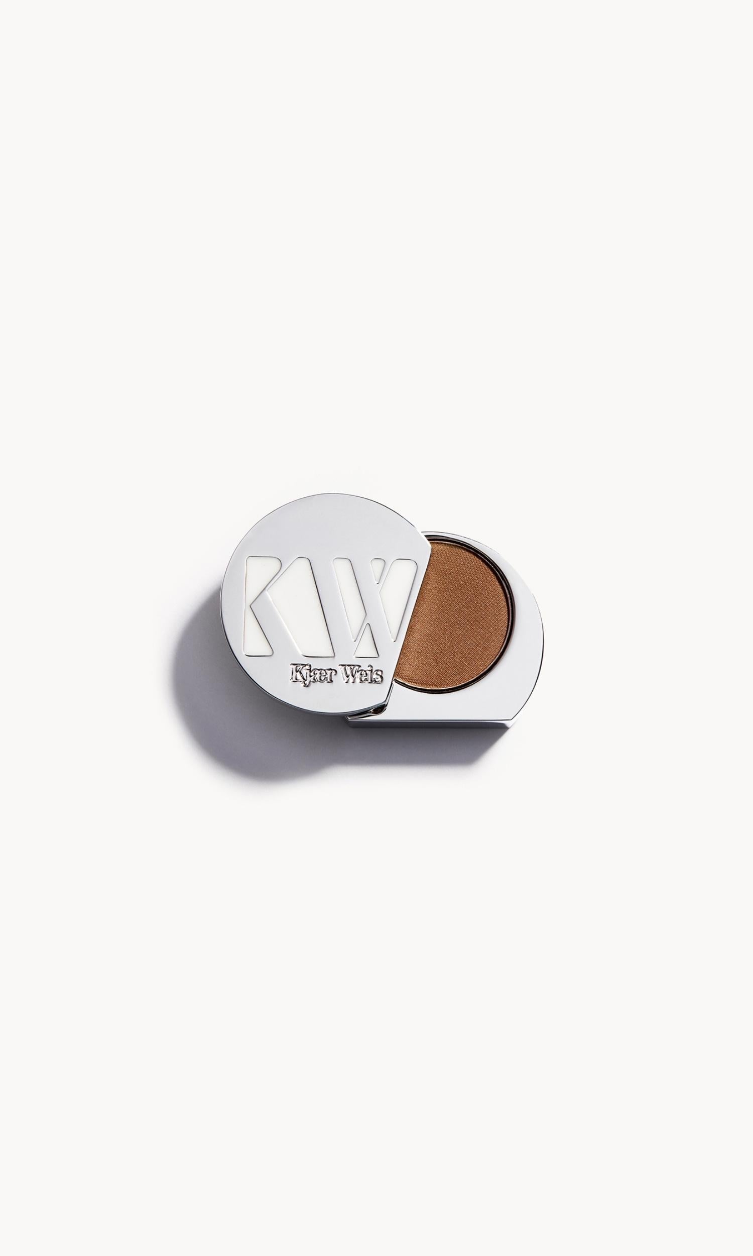 Solid metal KW palette with lid open to show brown-gold eye shadow inside